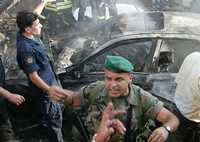 Un soldado intenta impedir el paso hacia el automóvil calcinado por la explosión en una calle de los muelles de Manara, en el sector musulmán de la capital del país árabe