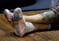 Un bailarín de la compañía Ballet Teatro del Espacio, con piernas tatuadas, durante un descanso