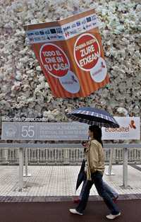 Dos personas caminan bajo un gran cartel de palomitas durante la 55 edición del Festival de Cine de San Sebastián