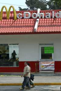 Jóvenes pasan frente a la sucursal de McDonald’s que fue clausurada