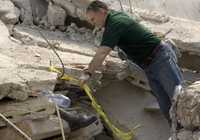 Un rescatista intenta sacar un cuerpo sepultado por los escombros en la escuela La Promesse