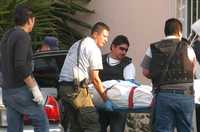 Personal del Servicio Médico Forense levanta el cuerpo de uno de los ejecutados afuera de un restaurante en León, Guanajuato