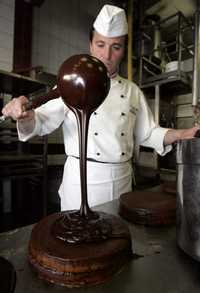 Fábricas italianas de alta calidad aprovechan el creciente apetito mundial por el chocolate gurmet, en tanto, un chef austriaco decora un pastel con salsa de este ingrediente en una repostería de Viena
