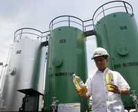 El secretario filipino de Energía, Raphael Lotilla, enseña muestras de biodiesel delante de tanques de premezclado durante la inspección a una productora del combustible en Manila, a principios de mes
