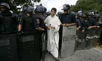 Un sacerdote pasa a través de un pelotón de la policía, ayer durante protestas contra Chávez en Caracas