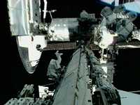 El astronauta John D. Olivas (al centro) trabaja en un costado de la Estación Espacial Internacional con la vista de la punta del Atlantis, en una imagen de video