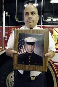 Un capitán de bomberos de Elsmere, Nueva York, posa con la foto de Shawn Martin, un marine muerto antier en combate en Irak. Antes de entrar al ejército el joven trabajó en el cuerpo de bomberos