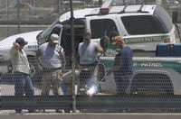 Trabajadores de la Border Patrol observan la reparación de la valla entre México y Estados Unidos, ayer en las inmediaciones del puente internacional Paso del Norte