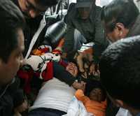 La lenta recuperación de cadáveres continúa en Pisco, en el sur del país. Abajo, brigadas de rescatistas asisten en Ica a una mujer y su hijita, heridas durante el movimiento telúrico