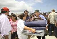 El presidente Felipe Calderón entrega un catre y cobijas a una de las pobladoras de Veracruz afectadas por el paso del huracán Dean