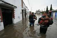 Una familia de damnificados de Tampico, Tamaulipas, trata de protegerse de la lluvia con periódicos