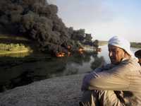 Iraquíes observan el incendio de una fuga de crudo que fue a parar al río Tigris, a su paso por Tikrit, al norte de Bagdad