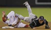 Kazuo Matsui, segunda base de Rockies, va a dar a la arcilla tras ser embestido por Mark Reynolds, de Diamondbacks, en jugada del cuarto episodio