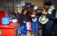 El presidente de Bolivia, Evo Morales (extremo derecho), y el presidente de Yacimientos Petrolíferos Fiscales Bolivianos, Guillermo Aruquipa, disfrutan una comida preparada por habitantes de El Alto, luego de inaugurar una red que proveerá de gas natural a más de 6 mil hogares de la región