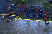Trabajadores de Pemex recogen gasóleo derramado en el río Coatzacoalcos por el rompimiento de un ducto