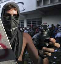 Un joven universitario muestra a la prensa una granada