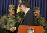 Juan Manuel Santos (al centro), ministro de Defensa colombiano, saluda al general Fredy Padilla, al término de una conferencia de prensa en Bogotá, en la cual se dio a conocer la muerte del número dos de las FARC