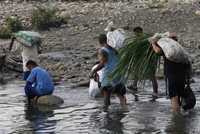 Colombianos con mercancías cruzan el río Táchira, frontera entre Colombia y Venezuela, en San Antonio, 880 kilómetros al oeste de Caracas