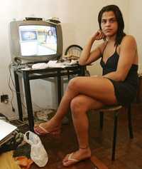 El travesti Andre Luis Ribeiro, conocido como Andrea Albertini, posa junto al televisor que da la noticia en la que lo involucran con Ronaldo