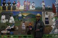 Juan González Hernández, pintor tzotzil conocido como Juan Gallo en su pueblo natal, San Juan Chamula, posa frente al mural que pintó en la Universidad Intercultural de Chiapas