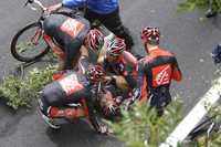 Óscar Pereiro es auxiliado por varios ciclistas tras chocar con vallas de protección y romperse un hombro y un fémur