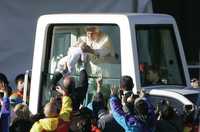 Benedicto XVI saluda a un bebé, durante su recorrido por Australia