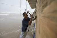 Un residente de Matamoros protege las ventanas de su negocio, ante la inminente llegada del huracán Dolly