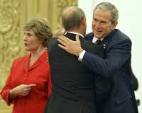 George W. Bush saluda en Pekín al primer ministro ruso Vladimir Putin en la inauguración de los Juegos Olímpicos. A la izquierda, Laura Bush