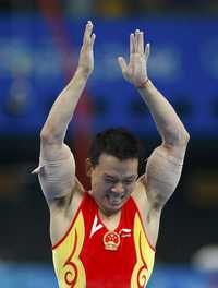 Huang Xu celebra al final de su rutina en las barras paralelas