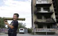 Un menor juega con una mukha –lanzagranadas– frente a un edificio dañado durante un ataque de Georgia en Tskhinvali, capital de la región separatista de Osetia del Sur