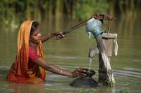 Una mujer recoge agua potable en la aldea inundada Godadhar, en Faridpur, Bangladesh, en julio pasado