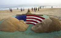 Turistas observan las esculturas de arena realizadas por el artista Sudarshan Patnaik con las figuras de los aspirantes a la Casa Blanca, en una playa de Puri, en India