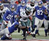 El corredor Brian Westbrook (36), de Filadelfia, es tacleado por James Butler, de Gigantes de Nueva York, que se coronó en la División Este de la NFC pese a caer, gracias al tropiezo de Vaqueros