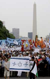 Manifestantes argentinos muestran carteles, entre ellos uno con los colores de la bandera israelí, con una leyenda escrita en español, ayer, durante una marcha en la embajada de ese país en Buenos Aires