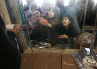 Mujeres reciben ayuda alimentaria de la ONU en un centro de distribución ubicado en el campo de refugiados de Shati, en la ciudad de Gaza
