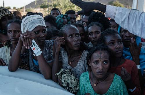 Etíopes que huyeron del conflicto en Tigray esperan la distribución de alimentos frente a un almacén en el campamento de refugiados de Um Raquba, en el este de Sudán. Más de 45 mil personas han escapado de la norteña localidad desde el 4 de noviembre, cuando el primer ministro Abiy Ahmed ordenó operaciones militares contra líderes del partido gobernante en Tigray en respuesta a sus presuntos ataques a bases del ejército federal.