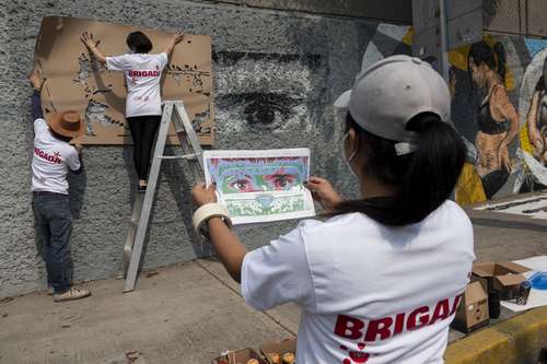 Alumnos y docentes de Artes y Diseño de la UNAM elaboran un mural en las paredes de la Escuela Nacional de Enfermería y Obstetricia como un homenaje al personal médico.