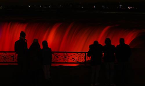 La gente pasa por lo alto de la cascada iluminada durante el Festival Anual de Luces de Invierno en las Cataratas del Niágara, Ontario.