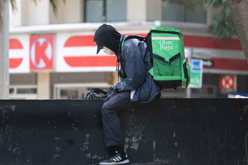 En Paseo de la Reforma, un repartidor de comida rápida revisa sus pedidos e itinerarios en tiempos de contingencia sanitaria.