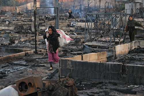 Una refugiada siria rescata algunas pertenencias del campamento de Al Miniyé, devastado por el fuego.