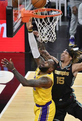 En el juego de Lakers contra Grizzlies, Brandon Clarke intenta evitar el enceste de LeBron James, quien anoche fue igualado en anotaciones por su compañero Anthony Davis.