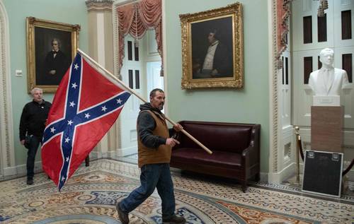 Un manifestante pro-Trump ingresó ayer al Capitolio con la bandera confederada, símbolo del racismo y la esclavitud en Estados Unidos. Foto Afp
