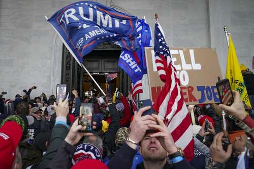 Seguidores de Donald Trump ondean una bandera con el nombre del aún presidente de Estados Unidos y se toman selfies.