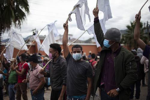 Migrantes hondureños levantan banderas blancas ante el ejército guatemalteco.