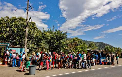 Migrantes venezolanos hacen fila para recibir alimentos y medicinas de un punto de apoyo de la Cruz Roja ubicado en una carretera en Cúcuta, Colombia, en la frontera con Venezuela. El gobierno del presidente Nicolás Maduro no tiene acceso a las reservas del país en el extranjero, lo que dificulta obtener fondos para costear vacunas en medio de la pandemia del Covid-19.