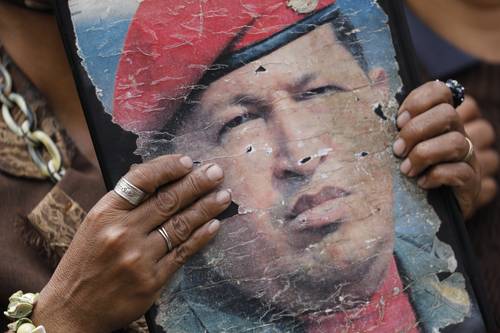 Asistente a la celebración del Día de la Juventud, ayer en Caracas, con un desgastado retrato del fallecido presidente Hugo Chávez.