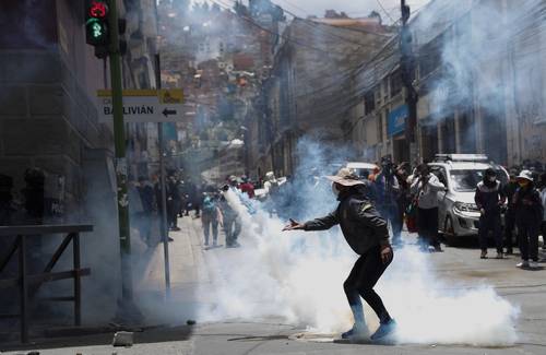 Un hombre devuelve un bote de gas lacrimógeno a la policía, durante una manifestación en apoyo a los trabajadores de la salud, en La Paz, Bolivia.