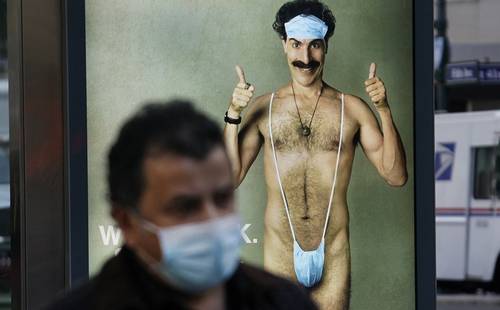 Un transeúnte pasa a un lado de un cartel promocional de Borat 2, cinta protagonizada por Sacha Baron.