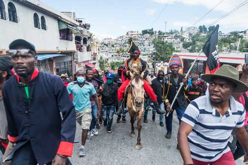 El líder del partido Pitit Desalin, Moise Jean Charles (al centro), monta a caballo mientras manifestantes haitianos marchan por las calles de Puerto Príncipe, para denunciar el aumento de los secuestros en los barrios cometidos por las pandillas y las inclinaciones por una nueva dictadura que el gobierno quiere instaurar según ellos.