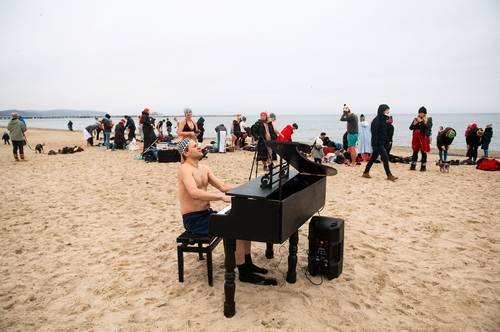 El pianista polaco Tomasz Szwelnik, vestido sólo con traje de baño, actúa durante el acto benéfico Sea of Angels para Mikolaj Charuk, un pianista discapacitado de 16 años, en la playa de Sopot, Polonia.